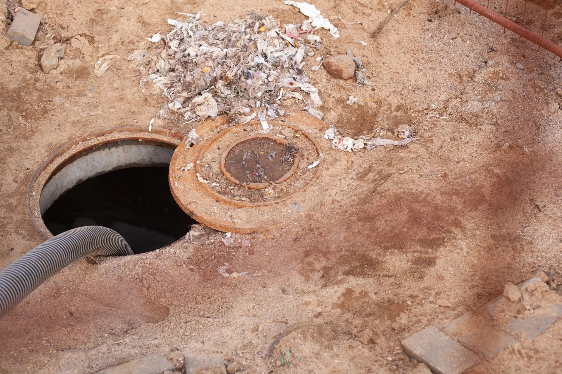 Septic tank lid open with the vacuum hose lowered in during a pump-out in Launceston